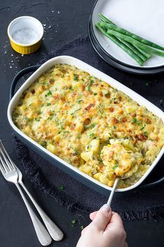 a casserole dish with potatoes and green beans in it on a black table