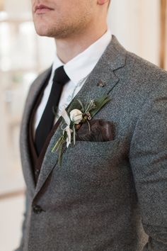 a man wearing a suit and tie with a boutonniere on his lapel