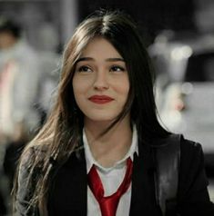 a woman with long hair wearing a red neck tie and black jacket, looking at the camera