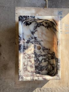 a marble sink sitting on top of a piece of cardboard next to a toilet paper roll