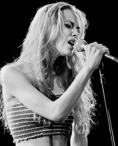 a black and white photo of a woman singing into a microphone