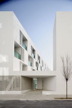 an empty parking lot in front of a building with white walls and balconies