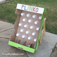 a cardboard box that is sitting on the ground with some cups in it and a board game inside