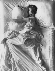 black and white photograph of a woman laying in bed with her head on the pillow