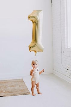 a toddler holding a balloon in the air