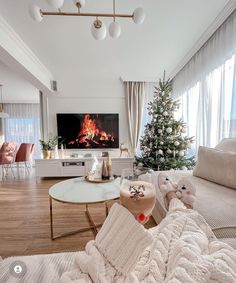 a living room filled with furniture and a flat screen tv mounted on the wall next to a christmas tree