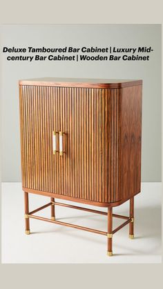 a wooden cabinet sitting on top of a white floor next to a wall with two gold handles