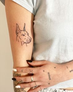 a woman's arm with a dog tattoo on the left side of her arm