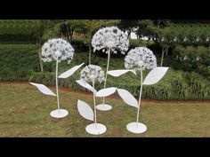 three white metal flowers are in the grass