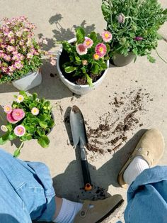 someone is digging dirt in the ground next to some potted flowers and gardening tools