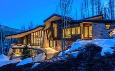 the exterior of a modern home in the mountains at night with snow on the ground