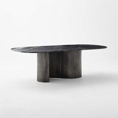 an oval dining table with a black marble top and curved metal base, against a white background