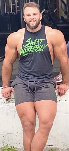 a man posing for the camera in his shorts and tank top with no shirt on