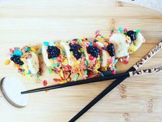 a wooden cutting board topped with lots of different types of food and chopsticks