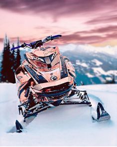 a snowmobile is parked in the snow at sunset