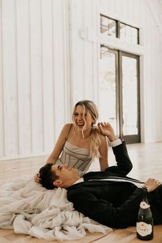 a man and woman laying on the floor next to each other with a bottle of beer