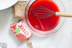 a bowl filled with red liquid and whisk on top of a white counter