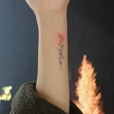 a woman's arm with a small flower tattoo on the left side of her wrist