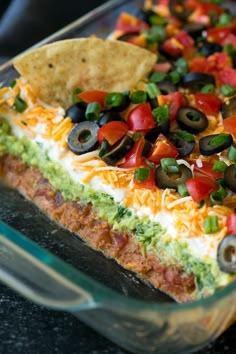 an enchilada dish with tortilla chips and olives on top