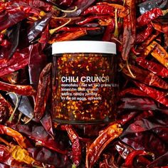 chilli crunch in a jar surrounded by red peppers