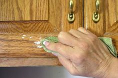 a person wiping up dust off the top of a kitchen cabinet door with a rag