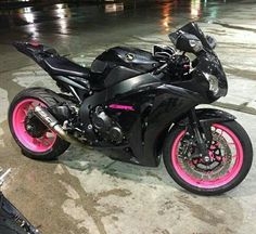 a black motorcycle with pink rims parked on the street