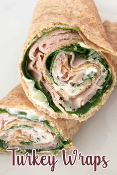 there is a wrap with meat and spinach in it on the white plate that says turkey wraps