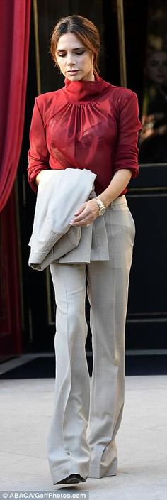 the woman is walking down the sidewalk with her hand in her pocket and wearing a red blouse