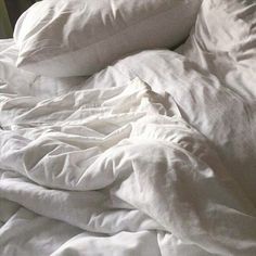 an unmade bed with white sheets and pillows