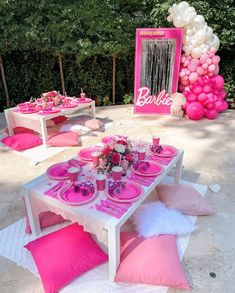 a table set up with pink and white decorations for a barbie birthday party in the backyard