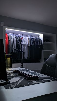 a desk with a laptop computer on top of it next to a closet full of clothes