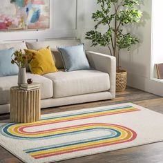 a living room with a white couch and colorful rugs on the floor next to a potted plant