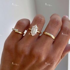 a woman's hand with three different rings on her fingers and one is wearing a diamond ring