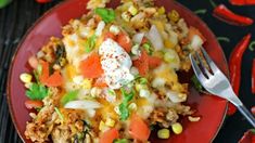 a red plate topped with mexican rice and veggies next to a knife and fork