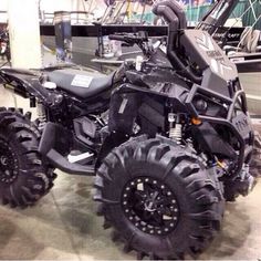 a black four - wheeler is parked in a showroom with large tires on it