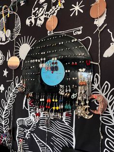 an assortment of earrings are hanging on a wall with black and white designs behind it