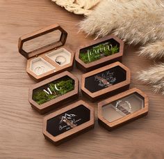 four wooden boxes with wedding rings and their names on them, sitting on a table