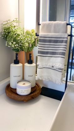 a bathroom sink with soap and lotion bottles on it next to a towel rack