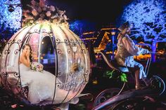 a woman in a white dress is riding on a horse drawn carriage with a man standing next to her