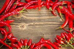 red chili peppers arranged in the shape of a circle on a wooden background with space for text