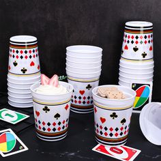 a table topped with cups filled with white frosting and playing cards on top of it