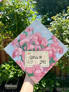 a hand holding up a graduation cap with flowers on it and the words class of 2011