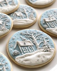 cookies decorated with icing and frosting are arranged on a plate in the shape of houses, trees, and snowflakes