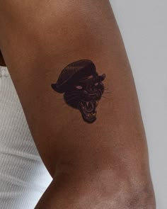 a woman's arm with a tattoo of a black cat wearing a hat on it