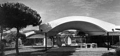 an old black and white photo of a building with trees in the foreground,