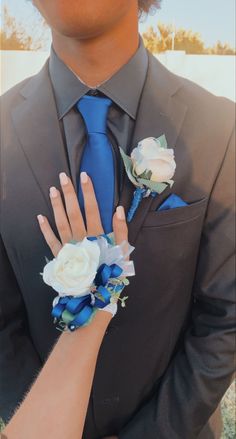 a man in a suit and blue tie with flowers on his lapel flower cuff