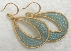 two pairs of gold tone earrings with blue glass beads and wire wrapped around the ends