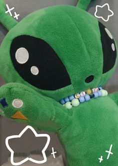 a green stuffed animal with white dots on it's eyes