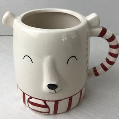 a ceramic mug with a bear's face painted on the side and stripes around it