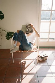 a person sitting in a chair with their feet up on the floor and reading a book